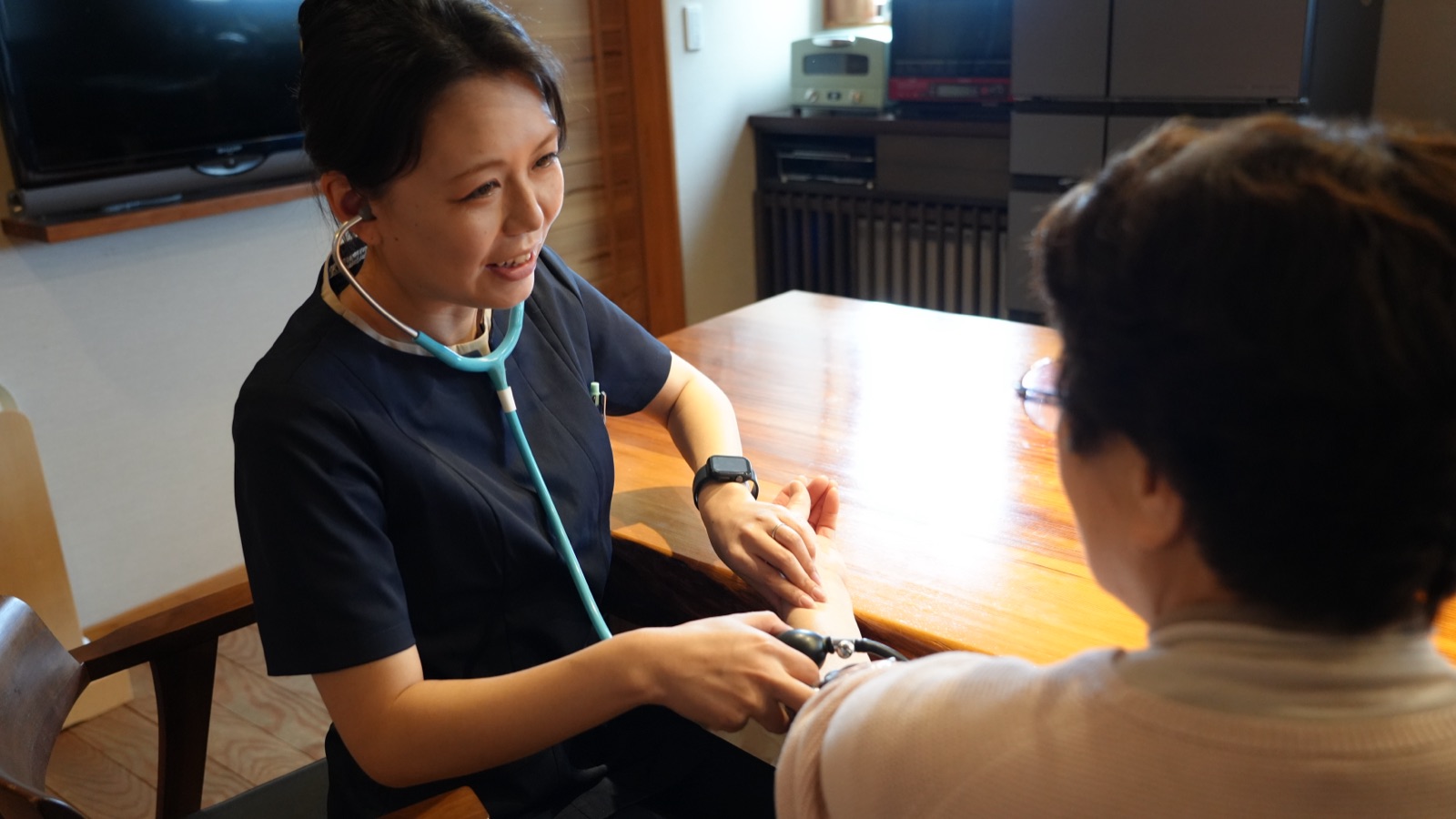 ご自宅で血圧を測りながら話を聞くiHomeの看護師